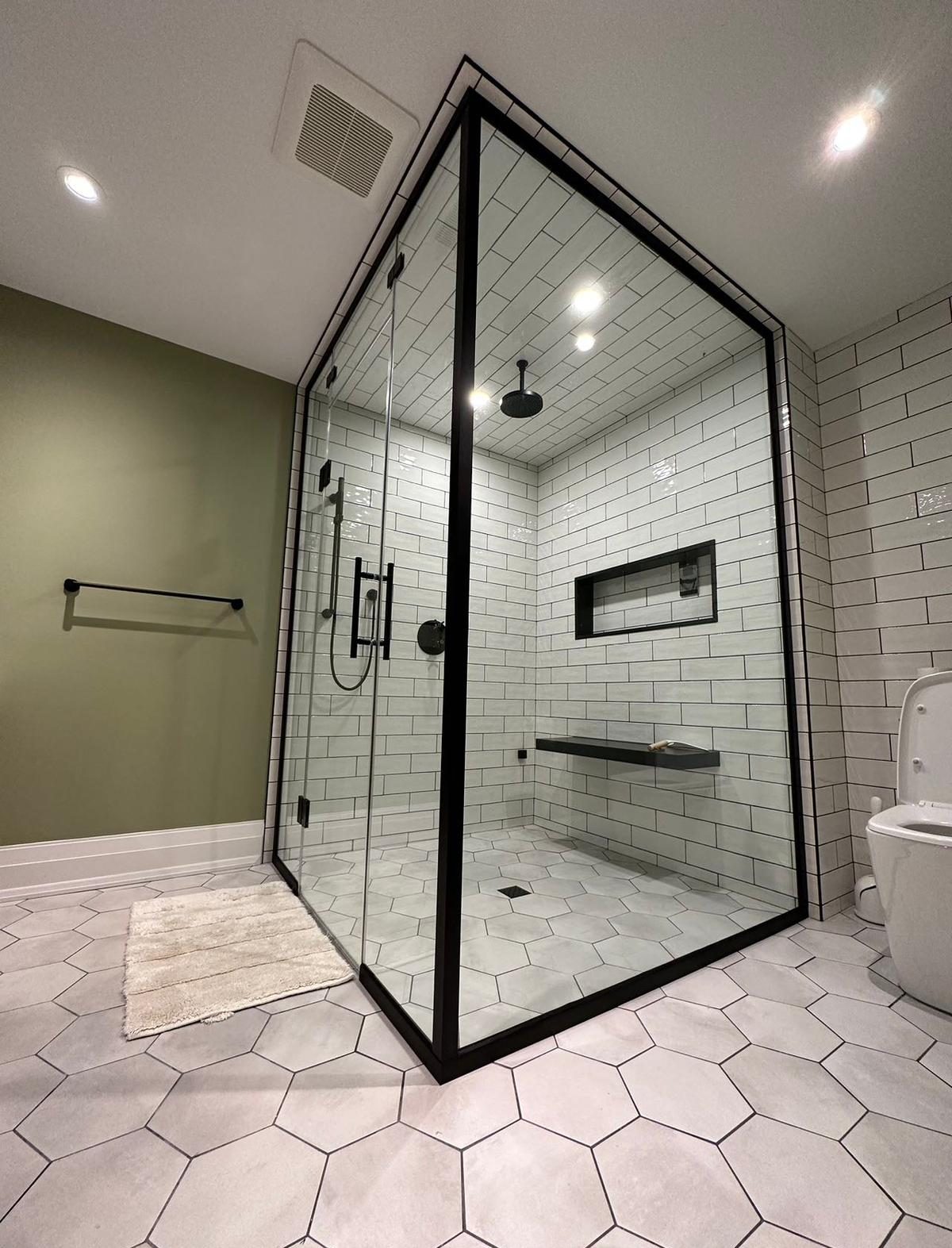 Custom black and white shower with a niche, bench, waterfall shower and custom glass